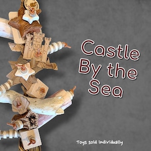 May include: A vertical bird toy featuring natural wood pieces, white star-shaped elements, and a laser-cut wooden castle shape. The toy includes textured driftwood, small wooden blocks, and striped beads strung together. Text reads Castle By the Sea.