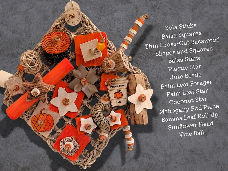 May include: A square woven seagrass mat bird toy featuring orange and natural wood elements including balsa stars, squares, sola sticks, jute beads, a palm leaf forager, coconut star, mahogany pod, banana leaf roll, and a pumpkin spice latte tag.