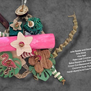May include: A bird toy featuring a pink wooden cylinder, a green vine ball, a coconut husk flower, a wooden star, and a flamingo cutout. It includes jute beads, a sola stick, a palm leaf crinkler, balsa squares, and basswood shapes on a jute rope.