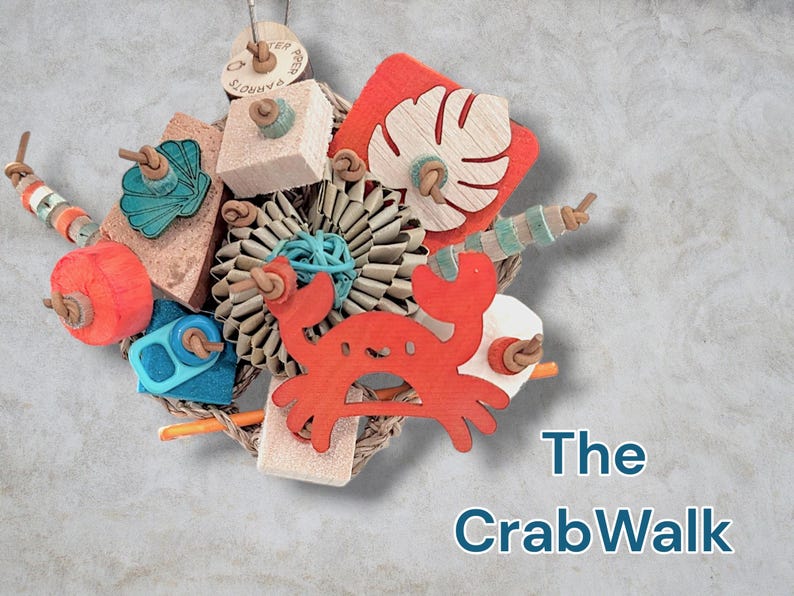 May include: A bird toy titled The CrabWalk featuring a central red wooden crab cutout, a pleated paper flower, a monstera leaf shape, and various colourful wooden blocks, beads, and teal shell accents strung together on a natural fibre rope base.