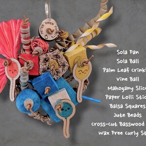 May include: A bird toy featuring a pink sola fan, a red vine ball, blue and yellow balsa squares, jute beads, mahogany slices, and paper lolli sticks with balloon illustrations. It includes a wax-free curly straw and basswood shapes.