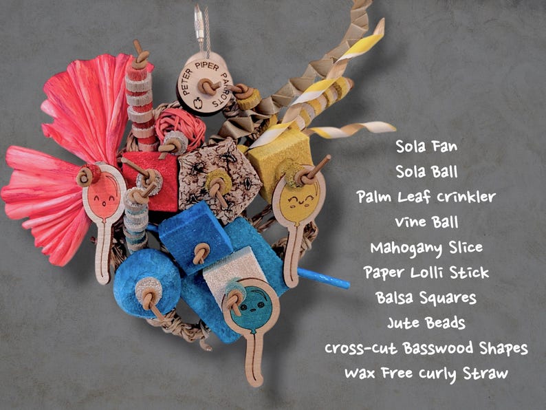 May include: A bird toy featuring a pink sola fan, a red vine ball, blue and yellow balsa squares, jute beads, mahogany slices, and paper lolli sticks with balloon illustrations. It includes a wax-free curly straw and basswood shapes.