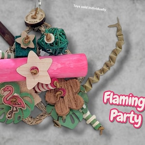 May include: A bird toy featuring a bright pink wooden log, a light-coloured wooden star, a green woven ball, and a flamingo cutout on a green leaf. It includes a brown flower shape, striped beads, and a zigzag paper strip. Text reads Flamingo Party.