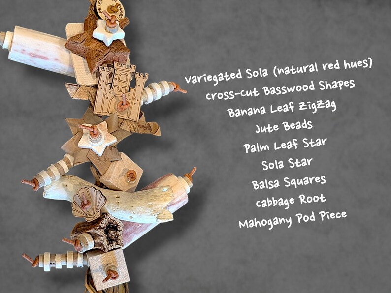 May include: A bird toy featuring variegated Sola with natural red hues, cross-cut Basswood shapes, a banana leaf zigzag, jute beads, a palm leaf star, a Sola star, balsa squares, cabbage root, and a mahogany pod piece, all strung together.