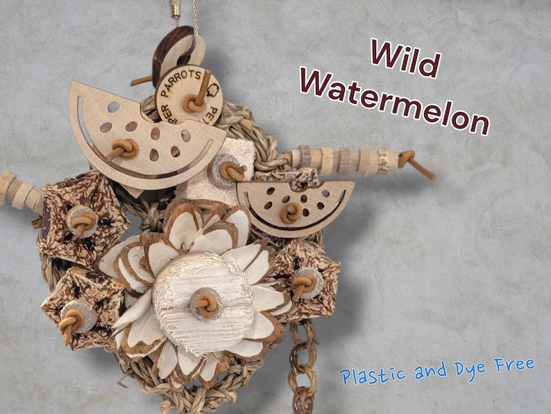 May include: A bird toy featuring wooden watermelon slices, textured bark pieces, and a central flower-shaped wood element, all strung together with natural fibres. The text Wild Watermelon and Plastic and Dye Free is visible on the image.