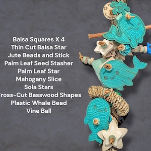 May include: A bird toy featuring turquoise whale shapes, balsa squares, a thin cut balsa star, jute beads, a stick, a palm leaf seed stasher, a palm leaf star, a mahogany slice, sola stars, cross-cut basswood shapes, a plastic whale bead, and a vine ball.