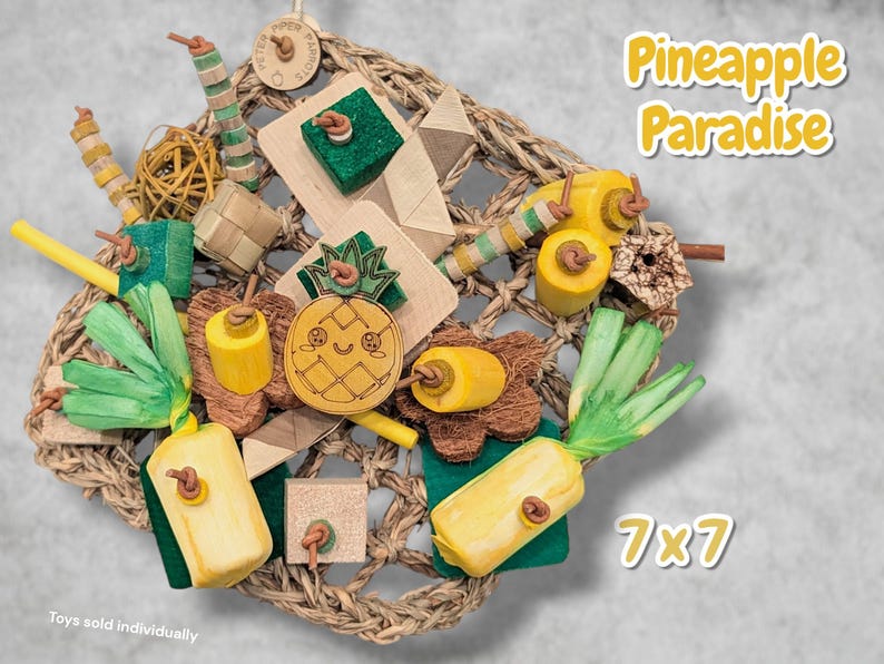 May include: A Pineapple Paradise bird toy set featuring a woven seagrass mat, wooden pineapple shapes, green paper shred, yellow wooden cylinders, and textured blocks. The set includes various natural materials and measures 7x7 inches.