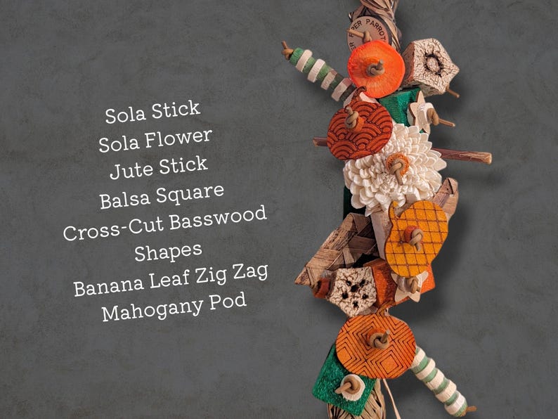 May include: A bird toy featuring a vertical arrangement of colorful components including a sola stick, sola flower, jute stick, balsa square, cross-cut basswood shapes, banana leaf zig zag, and a mahogany pod, with the text listing these materials.