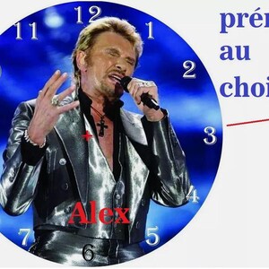 Könnte beinhalten: Ein blaues Zifferblatt mit weißen Zahlen und einem Bild eines Mannes, der in ein Mikrofon singt. Der Mann trägt eine silberne Jacke und eine schwarze Weste. Der Text "Alex" ist in Rot auf dem Zifferblatt gedruckt. Der Text "prénom au choix" ist in Blau über dem Zifferblatt gedruckt.