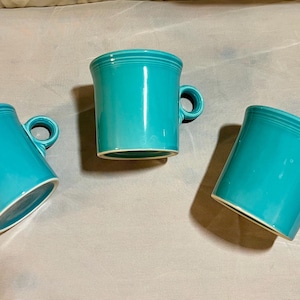 May include: Three turquoise ceramic mugs with handles. The mugs are all the same size and shape.