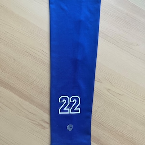 May include: Blue arm sleeve with the number 22 printed in white with a black outline. The sleeve has a small white logo with a letter G in the center.