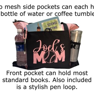 K&ouml;nnte beinhalten: Schwarze Tragetasche mit rosa Akzenten und dem Text "Joel's Mom" in rosa mit einem Baseball-Motiv. Die Tasche hat zwei seitliche Netztaschen, eine Fronttasche und eine Stiftschlaufe.