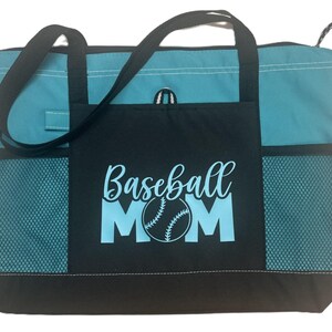 K&ouml;nnte beinhalten: Eine t&uuml;rkisfarbene und schwarze Tragetasche mit einem Netzfach auf jeder Seite. Das vordere Fach hat den Text "Baseball Mom" in hellblau mit einer Baseballgrafik.