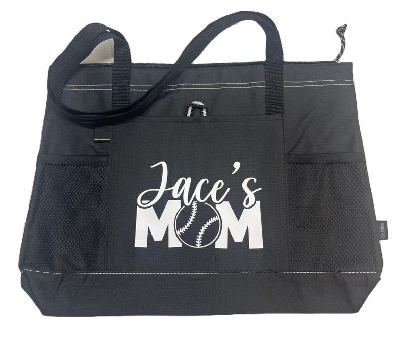 K&ouml;nnte beinhalten: Schwarze Tragetasche mit einem wei&szlig;en Baseball und dem Text "Jace's Mom" auf der Vorderseite.