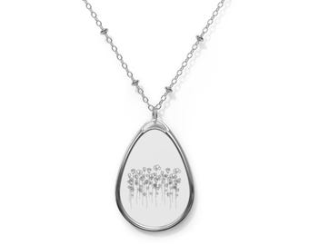 Puede incluir: Un collar de plata con un colgante en forma de lágrima que presenta un delicado dibujo lineal de un campo de flores.