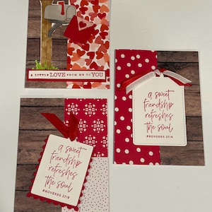 May include: Three handmade greeting cards featuring red, white, and wood-grain patterns. One card shows a mailbox with the text A LITTLE LOVE FROM ME TO YOU. Two cards feature tags with the text a sweet friendship refreshes the soul PROVERBS 27:9.