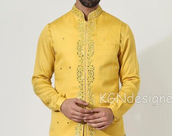 Op de afbeelding: Een mosterdgele kurta met een bijpassend geborduurd vest. Het vest heeft een ritssluiting en is versierd met gouden en zilveren versieringen. De kurta wordt gecombineerd met een witte broek en bruine loafers.