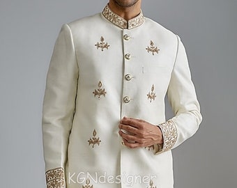 May include: A white embroidered jacket with gold detailing and a matching white pair of pants. The jacket has a mandarin collar and a button closure. The pants have a straight leg and a button closure.
