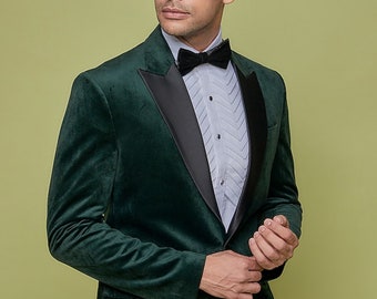 May include: A dark green velvet blazer with a black satin lapel and a black bow tie. The blazer has a single button closure and a pocket on the left side.