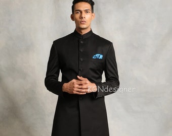 May include: A black long-sleeved jacket with a mandarin collar and button closure. The jacket has a pocket on the left side with a blue handkerchief. The model is wearing white pants and brown shoes.