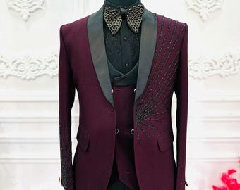 May include: A burgundy three-piece suit with a black satin lapel and black beaded embellishments on the jacket and sleeve.