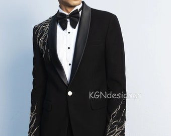 May include: A black tuxedo jacket with a satin lapel and silver embellishments on the sleeves. The jacket has a single button closure and a white shirt underneath.