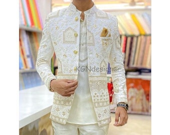 May include: A white blazer with intricate gold embroidery and a mandarin collar. The blazer has a single button closure and a pocket on the left side. The blazer is paired with white pants.