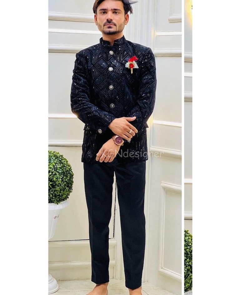 K&ouml;nnte beinhalten: Ein schwarzer Samtblazer mit geometrischem Muster und silbernen Kn&ouml;pfen. Der Blazer hat einen Stehkragen und einen einzigen Knopfverschluss. Das Model tr&auml;gt eine schwarze Hose.