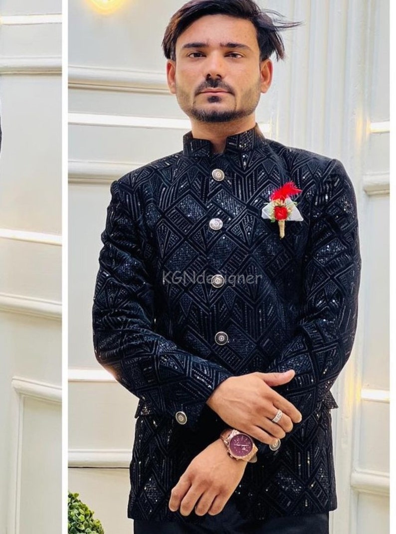 K&ouml;nnte beinhalten: Ein schwarzer Samtblazer mit geometrischem Muster und silbernen Kn&ouml;pfen. Der Blazer hat einen Stehkragen und eine kleine rote Blumennadel am Revers. Der Text "KGNDesigner" ist auf dem Blazer sichtbar.