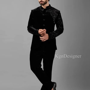 May include: A black velvet suit with a mandarin collar and a decorative design on the jacket. The suit is worn by a person with a beard.