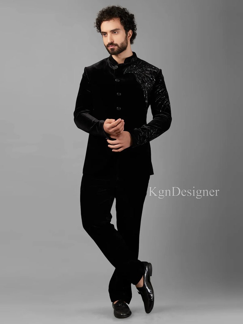 May include: A black velvet suit with a mandarin collar and a decorative design on the jacket. The suit is worn by a person with a beard.