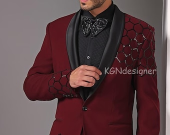 May include: A maroon suit jacket with a black satin lapel and black honeycomb pattern details on the sleeves and pockets. The jacket has a single button closure and a pocket on the left chest. The text "KGNDesigner" is visible on the jacket.