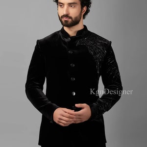May include: A black velvet blazer with a mandarin collar and a single button closure. The blazer features a black embroidered design on the right shoulder.