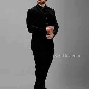 May include: A black velvet suit with a mandarin collar and button closure. The jacket features a decorative design on the front. The suit is worn by a person standing on a gray background. The text "KgnDesigner" is visible in the lower right corner of the image.