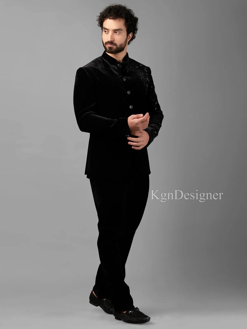 May include: A black velvet suit with a mandarin collar and button closure. The jacket features a decorative design on the front. The suit is worn by a person standing on a gray background. The text "KgnDesigner" is visible in the lower right corner of the image.