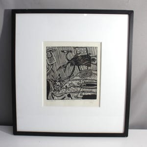 May include: Black and white framed print of a woodblock print depicting a fantastical scene with a creature with wings and a long tail. The print is framed in a black frame with a white mat.