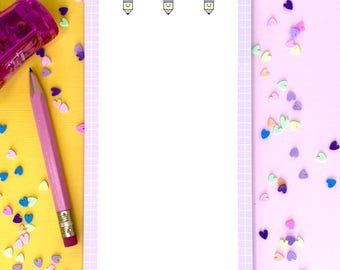 May include: A purple notepad with a grid pattern and a pencil design. The notepad is on a yellow and pink background with colorful heart-shaped confetti.