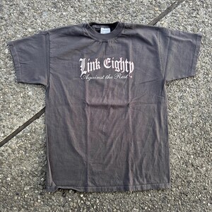 May include: A dark gray t-shirt with the text "Link Eighty Against the Rest" printed in white.