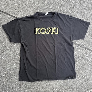 May include: Black t-shirt with a yellow graphic of the word "KOSKI" in a stylized font.