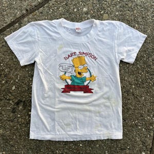 May include: White t-shirt featuring a yellow cartoon image of Bart Simpson from The Simpsons. The image includes the text "Don't have a cow, man!" and "Radical Dude".