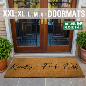 May include: A rectangular coir doormat with the phrase "Kindly. Fuck Off" in a cursive script. The mat is positioned in front of a wooden door. The image also features the text "XXL. XL. L. M. S DOORMATS" and a "NATURAL PLASTIC FREE" sign.