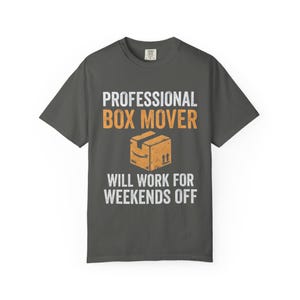 May include: Dark gray t-shirt with the text "PROFESSIONAL BOX MOVER" in white and orange, along with a graphic of a cardboard box. The text "WILL WORK FOR WEEKENDS OFF" is below the box graphic.