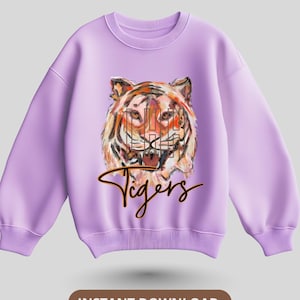 Könnte beinhalten: Ein lila Sweatshirt mit einer Aquarell-Illustration eines Tigers in Orange, Braun und Schwarz. Das Wort "Tigers" ist in Schreibschrift unter dem Tigerbild geschrieben. Der Satz "INSTANT DOWNLOAD" steht unten. Oben links befindet sich ein T-Shirt-Symbol.