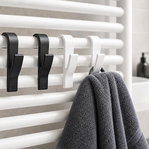 Puede incluir: Cuatro ganchos en forma de J diseñados para colgarse en un radiador tubular blanco. Dos ganchos son negro mate y dos son blanco mate. Una toalla gris oscuro cuelga de uno de los ganchos blancos. Los ganchos tienen una parte superior curva.