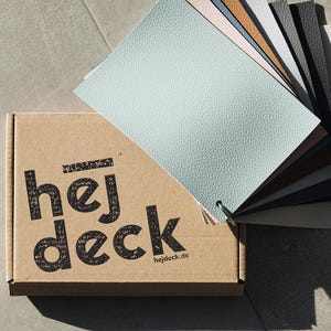 Könnte beinhalten: Ein Karton mit dem aufgedruckten Text "hej deck". Die Schachtel ist geöffnet und enthält einen Fächer mit Lederproben in verschiedenen Farben, darunter hellblau, rosa, braun, grau und schwarz.