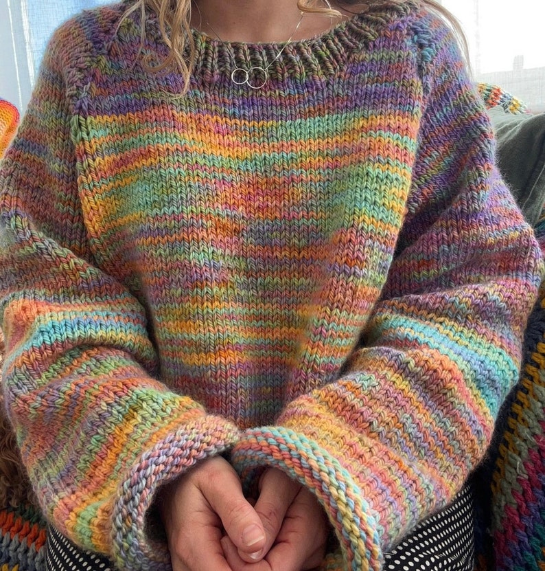 May include: A colourful striped jumper with a round neckline. The jumper is made from a soft, chunky yarn and has a relaxed fit.