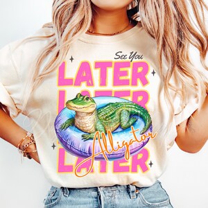Funny “See You Later Alligator” t-shirt PNG design with cute hand drawn watercolor alligator lounging in a pool float, retro pink and yellow text, summer vacation vibes, beach day shirt, animal humor tee, playful wildlife graphic tee, tropical novelty shirt, kids or adult funny alligator shirt, swamp theme apparel, southern charm gifts, Florida summer shirts, best-selling lake trip shirts, popular quirky animal t-shirt design PNG.