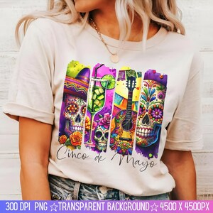 May include: A white t-shirt with a colorful graphic design featuring a guitar, a margarita glass, and a sugar skull. The text "Cinco de Mayo" is printed below the graphic.