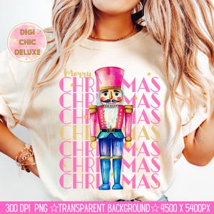 Hand-painted watercolor nutcracker soldier Christmas PNG design in vibrant pink, gold, and blue with festive stars and layered “Merry Christmas” lettering. Perfect for holiday shirts, Christmas party outfits, Nutcracker ballet gifts, winter home décor, festive wall art, seasonal apparel, cozy holiday decorations, and Christmas gift ideas for women and kids.