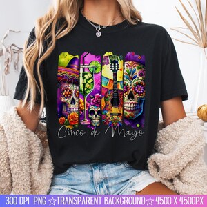 May include: Black t-shirt with a colorful graphic design featuring sugar skulls, a guitar, a margarita, and the text "Cinco de Mayo".